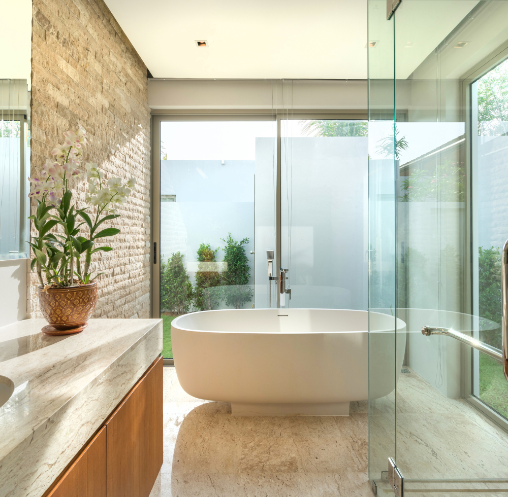 Modernes Badezimmer mit grossem Fenster, das auf den Garten des Hauses blickt.