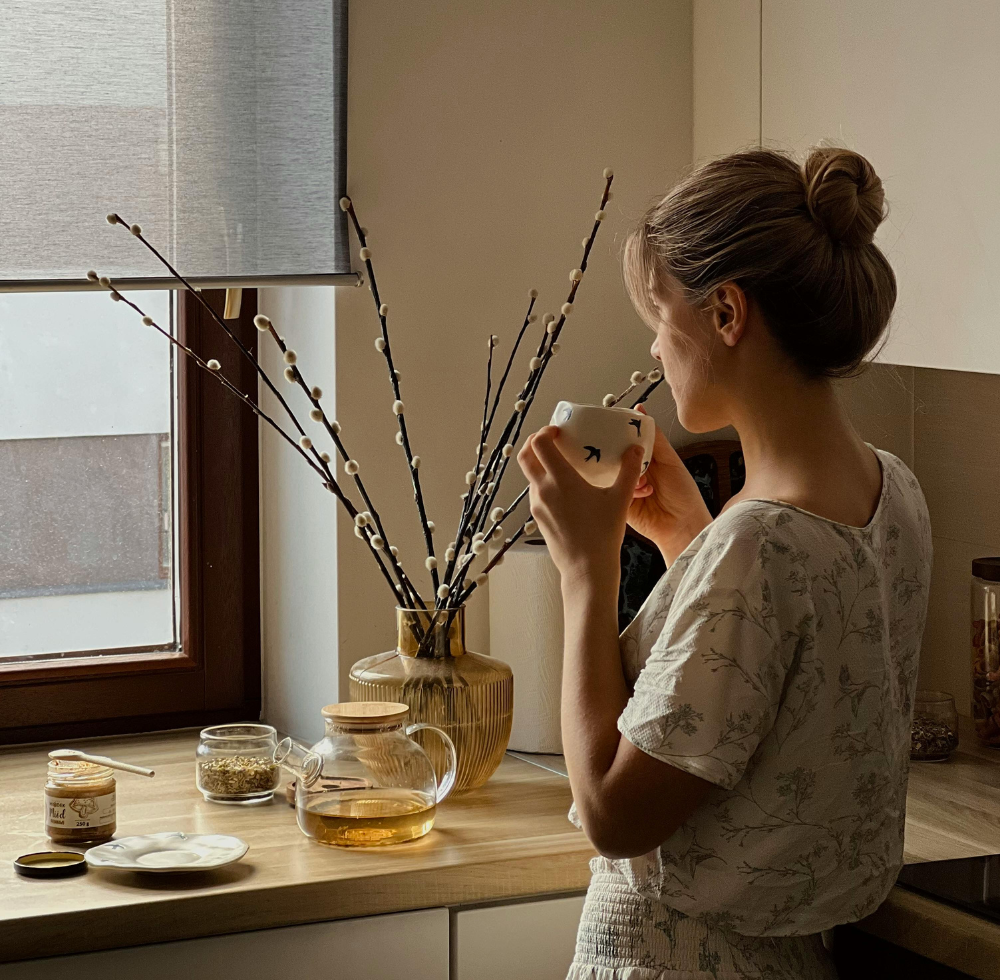 Junge Frau trinkt Tee in ihrer gut isolierten und ruhigen Küche